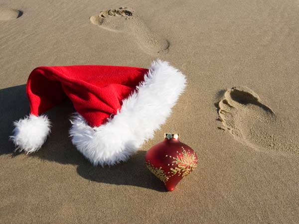 Santa hat and Christmas tree ornament on the beach.
