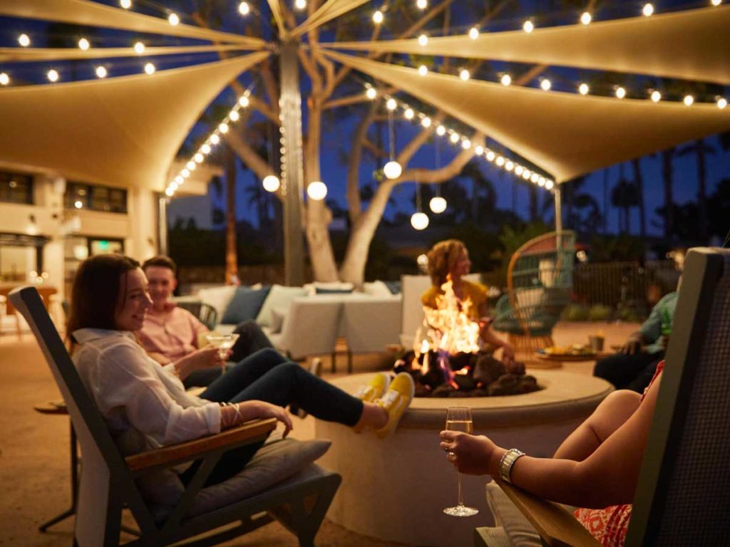 Friends sitting around a fire pit at Plaza Del Sol.