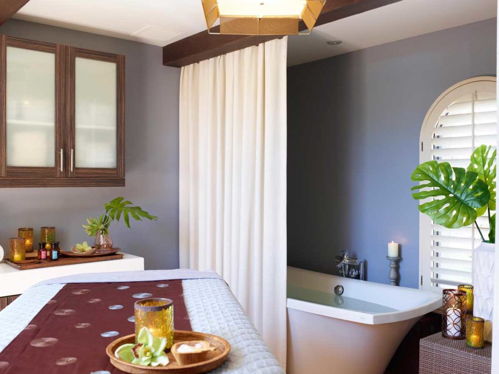 Spa room in San Diego with massage table and tub.