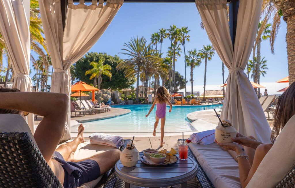 Girl Playing In The Pool While Parents Are In A Cabana