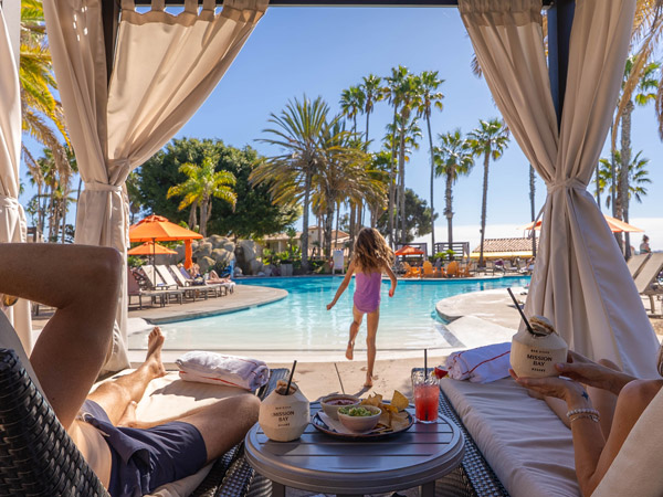 Girl Playing In The Pool While Parents Are In A Cabana