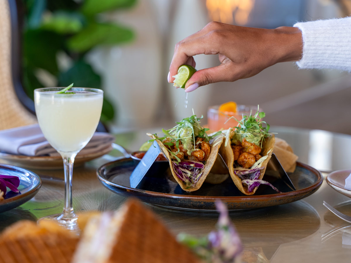man putting lime juice over tacos
