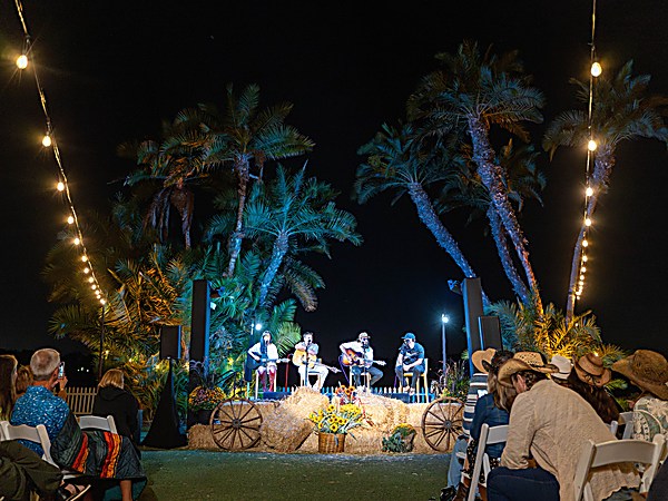 Live acoustic concert at night under palm trees and string lights at San Diego Mission Bay Resort with guests seated for an outdoor music event