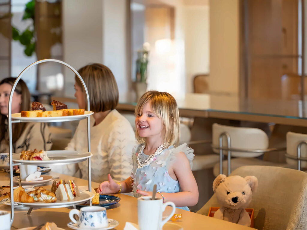 Girl enjoying a tiered afternoon tea service with a teddy bear at San Diego Mission Bay Resort.