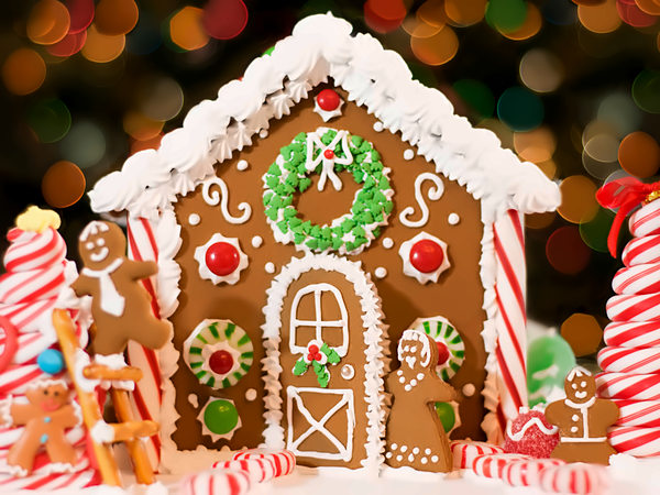 Decorated gingerbread house with holiday lights behind it at San Diego Mission Bay Resort.
