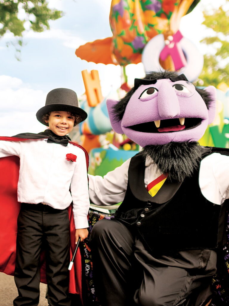 Young boy in a vampire costume and top hat posing with a costumed character at a family Halloween celebration near San Diego Mission Bay Resort.