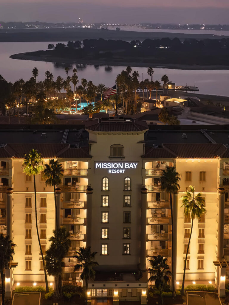 Illuminated guest tower and bayfront grounds at twilight at San Diego Mission Bay Resort.