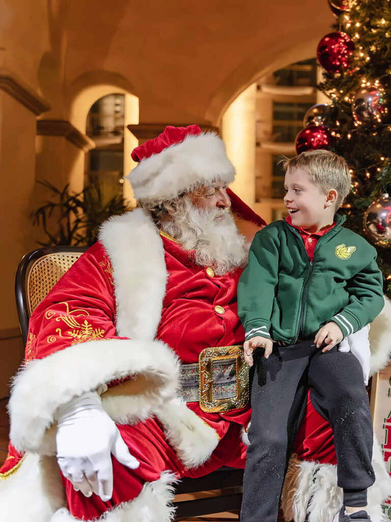 Santa and a young boy by a decorated Christmas tree at San Diego Mission Bay Resort.